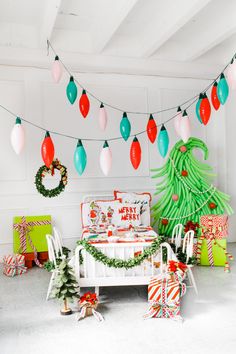 a room decorated for christmas with decorations and presents on the floor, lights hanging from the ceiling