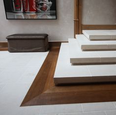 a room with white tiles and wooden steps leading up to a painting on the wall