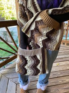 a woman is standing on a deck holding a crocheted bag