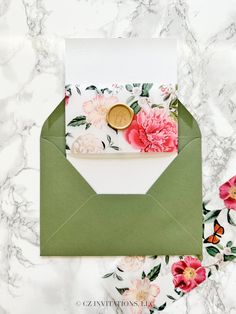 an envelope with flowers and a wax stamp on the inside is sitting on a marble surface