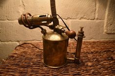 an old fashioned lamp is sitting on a wicker tablecloth next to a brick wall