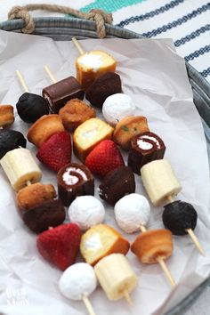 several desserts are arranged on skewers with strawberries and other toppings