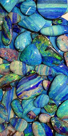 blue and green glass pebbles are stacked on top of each other in a pile together