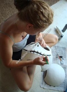 a woman sitting on the floor with a fake toothbrush in her hand next to a skull