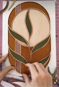 a person is making a stained glass flower design on a piece of paper with scissors