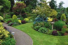 a garden filled with lots of different types of flowers and plants on top of green grass