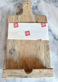 a wooden cutting board with some red and white stickers on the top of it