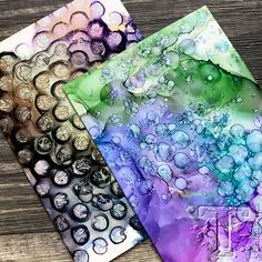 three different colored papers with water drops on them