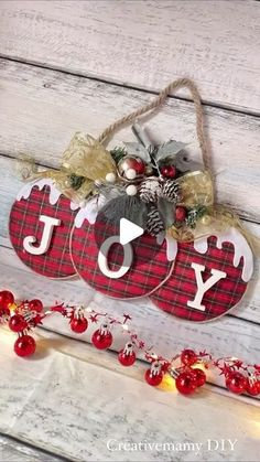 a wooden sign with the word joy hanging from it's side next to christmas decorations