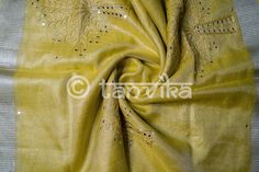 This elegant tissue linen drape in a beautiful gold tone features the beautiful and meticulously done floral cutwork design. This saree has pretty faux mirror (flattened sequin discs) work which adds a lovely vibe and bling to the whole outfit. The saree might have slight irregularities in the pattern & colors, which results from the human involvement in the process & is a hallmark of handcrafted products. Minor thread pulls are not considered damage. We recommend professional dry cleani Celebration Tussar Silk Saree With Gota Work, Tussar Silk Saree With Gota Work For Celebrations, Elegant Tussar Silk Dupatta With Mirror Work, Celebration Tussar Silk Dupatta With Gota Work, Elegant Gold Tussar Silk Embroidered Fabric, Elegant Gold Embroidered Tussar Silk Fabric, Silk Embroidered Fabric With Chikankari In Gold, Gold Silk Fabric With Chikankari Embroidery, Elegant Silk Fabric With Gota Embroidery