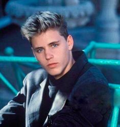 a young man sitting on top of a blue bench