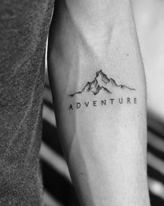 a man's arm with the words adventure on it and mountains in black ink