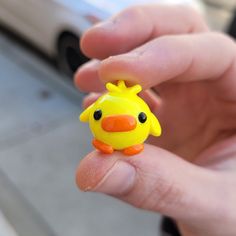 a small yellow toy duck sitting in the palm of someone's hand