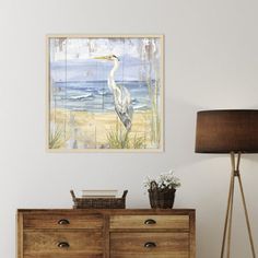 a painting on the wall above a dresser in a room with a lamp and vase