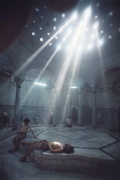 two people are laying on the ground in a dimly lit room with beams of light coming from above