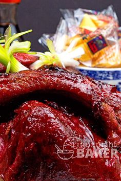 a large piece of meat covered in sauce next to other food items on a table