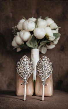 a pair of high heeled shoes sitting next to a bouquet of flowers