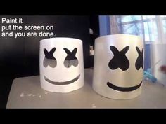 two coffee mugs with faces painted on them, one is white and the other is black