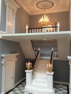 a staircase with chandelier and stairs leading up to the second floor