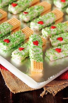 some green and white desserts are on a silver platter with red hearts in the middle