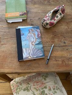 a wooden table topped with books next to a pair of slippers and a purse