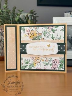 a close up of a card on a table with flowers and plants in the background