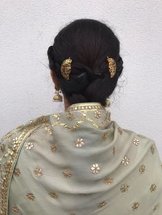 the back of a woman's head with gold hair clips on her left side