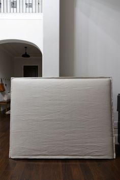 a white couch sitting on top of a hard wood floor next to a stair case