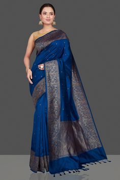 Gorgeous dark blue tussar Banarasi saree with antique zari buta border and pallu. It comes with a red blouse piece. Shop handwoven sarees in USA from Pure Elegance. The shown stitched blouse on the model is for display purpose only. The saree comes with a matching blouse piece and finished with fall and piko. Disclaimer: The actual product may vary slightly from the image. These are custom orders, hence expect slight variation in color, placement of the motif or buta. ESTIMATED DELIVERYBecause this is a custom order, it would take about 4 weeks from the date of purchase. RETURN POLICYThis product is a custom order and cannot be returned or exchanged. Blue Slub Silk Saree With Zari Work, Blue Slub Silk Pre-draped Saree With Zari Work, Blue Traditional Wear In Slub Silk With Self Design, Royal Blue Banarasi Silk Saree With Zari Work, Blue Slub Silk Saree In Traditional Drape, Blue Slub Silk Pre-draped Saree With Zari Weaving, Royal Blue Banarasi Silk Saree With Cutdana, Blue Slub Silk Traditional Wear For Puja, Blue Slub Silk Saree With Zari Weaving