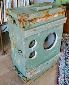 an old green box sitting on top of a wooden floor next to a book shelf