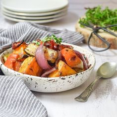 a white bowl filled with vegetables on top of a table next to plates and utensils