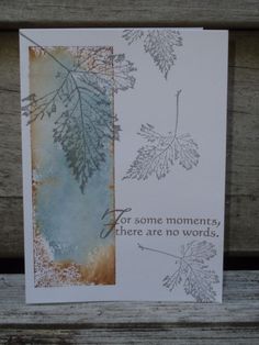 a card with leaves on it sitting on top of a wooden bench next to a piece of paper