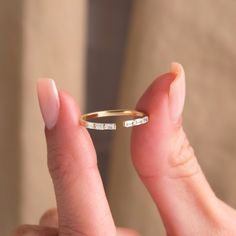 a person holding a gold ring with two small diamonds on the inside and outside of it