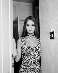 a woman standing in front of a door wearing a leopard print dress and choker