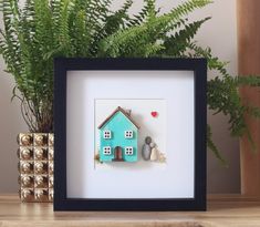 a blue house with two rocks in front of it on a shelf next to a potted plant