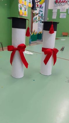 two graduation hats made out of toilet paper with red ribbon tied around the top and bottom