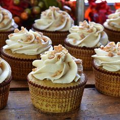 several cupcakes with white frosting and nuts on top are sitting on a wooden table