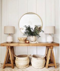 a wooden table topped with baskets under a mirror