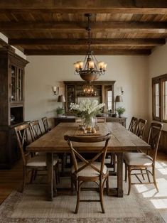 a dining room table with chairs and a chandelier hanging from the ceiling above it