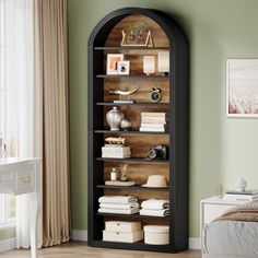 an arched bookcase in the corner of a room with green walls and wooden floors