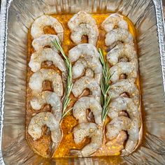 cooked shrimp in a baking dish with rosemary sprigs on top and seasoning