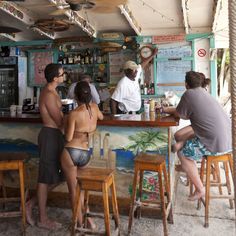 three people sitting at a bar in the sand