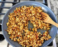 a pan filled with food sitting on top of a stove next to a wooden spoon