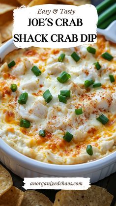 a close up of a bowl of crab dip with crackers and green onions on the side