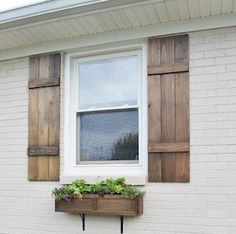 a white brick house with shutters and window boxes filled with plants on the outside