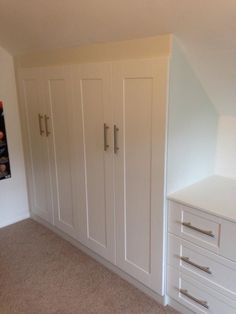 an empty room with white cabinets and drawers