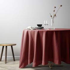 a table with a red cloth on it next to a small wooden stool and white wall