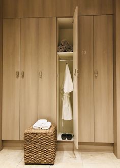 a bathroom with wooden cabinets and white towels on the shelf, next to a wicker laundry basket