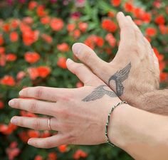 two hands that have tattoos on them and one is holding the other's hand