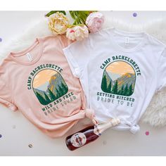 two t - shirts with the words lake bachelors on them next to a bottle of wine